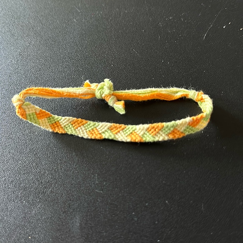 Handmade woven bracelet. Orange, green, yellow. Braided pattern